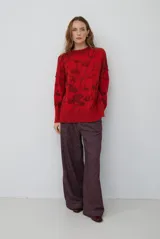 Buzo de tejido de punto con cuello redondo, mangas largas con puños acanalados y diseño estampado de flores en tonos rojos.
