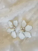 Par de aros colgantes con forma de flor blanca con borde plateado y centro de perlas y cuentas plateadas.