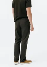 Pantalón de vestir color verde oscuro, de corte slim, con bolsillos laterales y traseros. Se ajusta a la cintura con botón y cierre.