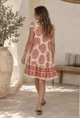 Vestido corto beige de corte oversized, con escote en V, mangas cortas y estampado geométrico en tonos mostaza.