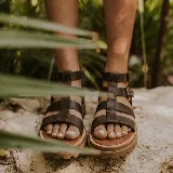 Sandalias romanas de cuero color marrón, con diseño de múltiples tiras horizontales y verticales, doble hebilla lateral de ajuste y suela track de goma.
