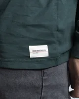 Remera de manga larga en color blanco, con cuello redondo y corte clásico. Presenta un pequeño detalle de etiqueta cosida en el puño de la manga.