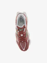 Championes New Balance modelo 9060, con diseño inspirado en la estética tecnológica del año 2000. Presenta una combinación de colores en tonos rojizos, con detalles en verde y blanco. Cuenta con mediasuela ergonómica con amortiguación ABZORB y SBS, y barras estabilizadoras ampliadas.