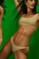 Conjunto de bikini color nude de tela morley. El corpiño es tipo top con elástico en el bajo busto, escote amplio y breteles fijos. La bombacha es vedetina con frente en V.