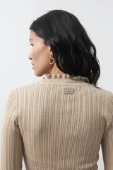 Polera de tejido acanalado color negro, con cuello alto y puños con terminación de volados. Presenta un diseño entallado y textura vertical.