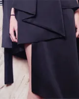 Falda midi negra de seda triple, de tiro medio y corte asimétrico. Presenta tres tablones en la parte delantera que definen el largo irregular del diseño.