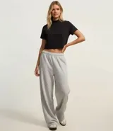 Blusa tipo t-shirt cropped de color beige, con cuello alto y mangas cortas. Confeccionada en algodón con elastano, presenta un diseño básico y ajustado.
