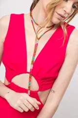 Vestido corto fucsia con escote en V y corte a la cintura. Presenta aberturas laterales y lazo ajustable en la espalda.