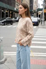 Sweater de punto con diseño de cuadros en tonos marrón y beige, de cuello redondo y manga larga.