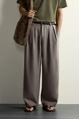 Pantalón relaxed fit de color blanco off-white, confeccionado en tejido con lino. Cuenta con pliegues frontales en la cintura, bolsillos delanteros y cierre frontal con cremallera y botón.