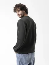 Buzo de cuello redondo verde oscuro, de manga larga, con detalle de costura en V en el cuello y pequeño parche engomado con la marca en el pecho.
