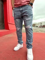 Pantalón mom jean de corte oversize para hombre, con roturas en las rodillas y lavado ácido en tono celeste.