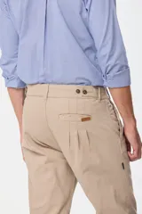 Pantalón de vestir color verde oliva, de corte recto, con bolsillos laterales y traseros. Se ajusta a la cintura con cinturón de cuero marrón.