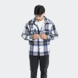 Camisa de franela a cuadros en tonos grises, blancos y negros, forrada con corderito sintético en el interior. Cuenta con mangas largas, bolsillos con solapa en el pecho y cierre frontal con botones.