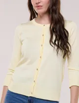 Cardigan de punto fino color amarillo con escote a la base, mangas tres cuartos y abotonadura frontal con botones metálicos decorativos.