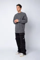Pantalón tipo carpintero de corte relaxed fit y tiro medio, confeccionado en denim negro con costuras a contracolor en blanco. Presenta múltiples bolsillos cargo laterales, un bolsillo con cierre en la parte inferior y presillas utilitarias.