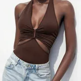 Body marrón con escote halter, detalle de frunce en el centro y aberturas laterales en la cintura.