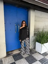 Buzo oversize gris melange de punto fino, con escote redondo amplio que se puede usar caído sobre un hombro, mangas largas amplias y diseño asimétrico más largo en la espalda.