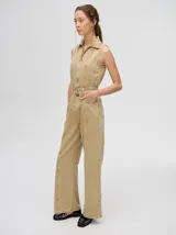 Mono largo de denim azul con corte holgado, recto en las piernas y entallado en el tronco. Tiene cuello camisero, cierre frontal con cremallera y cinturón ajustable.