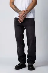 Jean de corte mom oversize, color negro lavado, con diseño de cinco bolsillos y cierre frontal con botón y cremallera.