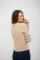 Buzo de tejido de punto color beige, con cuello redondo, manga larga y terminación de ruedo con diseño ondulado.