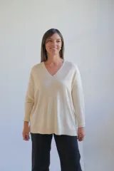 Sweater de punto color crudo, con escote en V, manga larga y diseño holgado con costura central vertical.