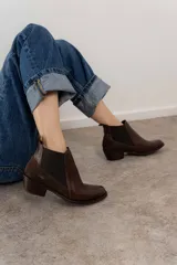 Bota corta de cuero color marrón con elásticos laterales, taco bajo y punta redondeada.