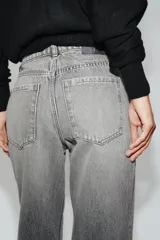 Jeans de tiro alto con cinco bolsillos, pernera recta y larga, confeccionados en denim negro con cierre frontal de cremallera y botón metálico.
