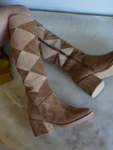 Botas de caña alta de gamuza color marrón, con diseño de rombos en tonos beige y marrón. Cuentan con cierre lateral y taco cuadrado.