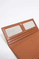 Billetera rectangular de piel en color naranja vibrante, con cierre de presión y logo de la marca estampado en letras doradas en la parte frontal. Cuenta con compartimentos interiores para tarjetas y monedas.