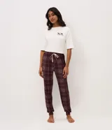 Pantalón de pijama estilo jogger color bordó con estampado de cuadros y pequeños corazones. Cuenta con cintura elástica ajustable mediante cordón y puños en los tobillos.