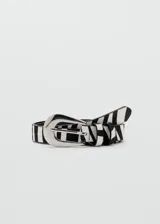 Cinturón de piel bovina con pelo, con estampado animal print de cebra en color blanco y negro, hebilla metálica plateada y pasador a juego.
