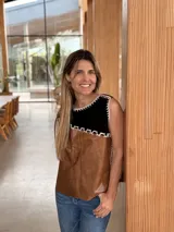 Chaleco sin mangas de diseño artesanal confeccionado con piezas de cuero marrón y negro unidas mediante costuras bordadas visibles. Presenta espalda tejida en hilo color marrón y corte recto.