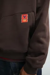 Sudadera con capucha de corte relajado, color marrón oscuro, con interior perchado. Presenta un bolsillo frontal tipo canguro, bordado con la palabra 'LOVE' en el pecho y un parche decorativo a contraste en el bolsillo. Posee puños y ruedo en rib.
