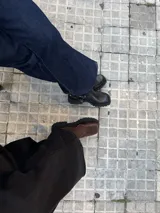 Botas tipo chelsea de caña baja, confeccionadas en una combinación de cuero gamuzado y cuero texturizado en tono marrón oscuro. Presentan una suela track de plataforma gruesa y elásticos laterales negros.
