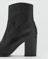 Botín de cuero vacuno color negro, con diseño de estilo western, punta fina y tacón bloque de 6,5 cm. Cuenta con cierre de cremallera lateral.