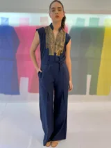 Mono largo azul marino con estampado dorado en la parte superior, cuello mao, sin mangas, con cinturón y bolsillos laterales.