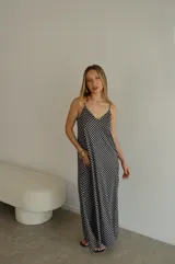 Vestido largo de jersey con estampado de lunares blancos sobre fondo negro. Presenta breteles finos, escote en V y un calce holgado y fluido.