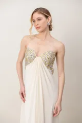 Vestido largo marfil de gasa, strapless, con bustier bordado en pedrería brillante y diseño drapeado en el frente.