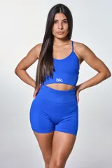Conjunto deportivo de dos piezas color azul, compuesto por un top corto con breteles finos y logo estampado, y un short de tiro alto ajustado al cuerpo.
