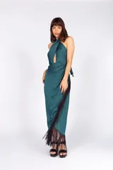 Vestido largo de seda lavada color verde esmeralda, con escote cruzado, falda en capas y flecos negros en el ruedo.