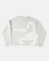 Suéter de punto color gris claro con diseño de escorpión en color blanco tejido en el frente. Presenta cuello redondo, puños y cintura con terminaciones acanaladas, y un corte holgado tipo boxy fit.