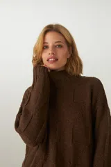 Buzo de tejido de punto industrial color marrón oscuro, con cuello medio y diseño de bloques cuadrados en relieve.