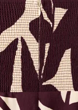 Monopieza sin mangas con escote palabra de honor, de corte recto y largo, con diseño estampado de hojas en tonos beige y bordó. Cuenta con cierre de cremallera en la parte posterior y forro interior.