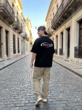 Remera negra de algodón con corte oversize y estampado frontal con la palabra "Blessed" en blanco y "by God" en rojo.