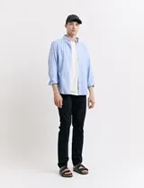 Camisa de corte clásico confeccionada en tejido oxford, con diseño de rayas verticales en tonos azul y blanco. Presenta cuello abotonado, cierre frontal con botones y bolsillo en el pecho con detalle de etiqueta bordada.