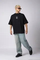 Remera negra de corte oversize con cuello redondo y mangas cortas. Presenta un pequeño estampado gráfico en color blanco en el centro del pecho.