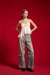 Musculosa de satén color blanco, con breteles finos regulables, escote en V decorado con detalles de encaje y diseño fluido.