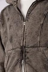Campera oversize con capucha y cierre frontal, confeccionada en tela con acabado acid wash que le otorga un aspecto desgastado. Presenta costuras curvas decorativas en el frente y la espalda, puños y ruedo acanalados, y un calce relajado.