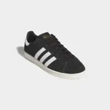Championes Adidas Jabbar Lo de diseño clásico y minimalista, con parte superior de cuero negro, las icónicas tres franjas laterales en blanco y suela de goma en tono crema.